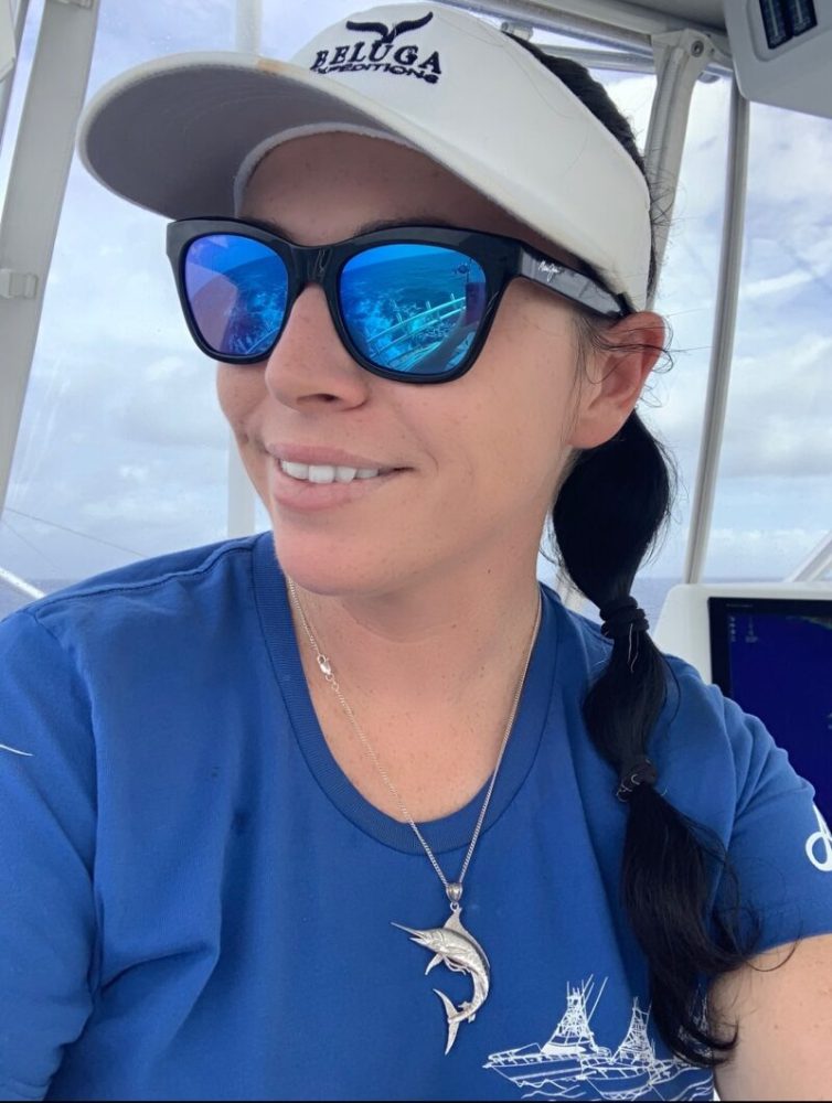 a woman wearing a hat and sunglasses posing for the camera