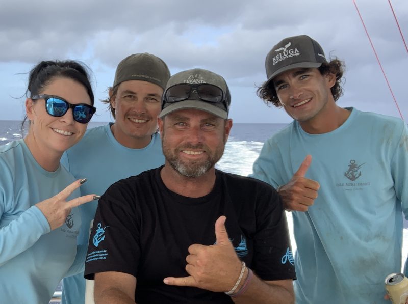 a group of people standing next to a person holding a fish